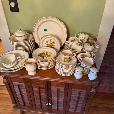Vintage stoneware dinnerware set featuring a yellow floral pattern, including plates, bowls, cups, saucers, and serving pieces,