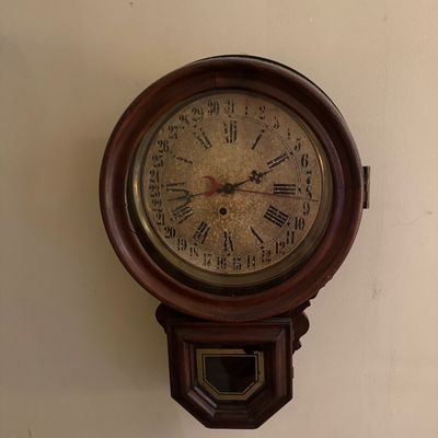 Antique Seth Thomas double-dial calendar wall clock in a dark wood case, featuring a weathered face with Roman numerals and outer date ring.