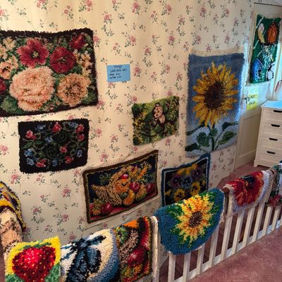 Collection of vintage handmade latch hook rugs featuring various floral, animal, and fruit designs,