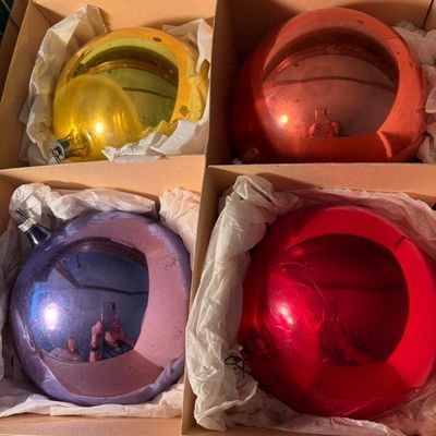 Sale Photo Thumbnail #88: Set of four vintage oversized glass Christmas ornaments in yellow, orange, purple, and red, nestled in their original cardboard divider box.