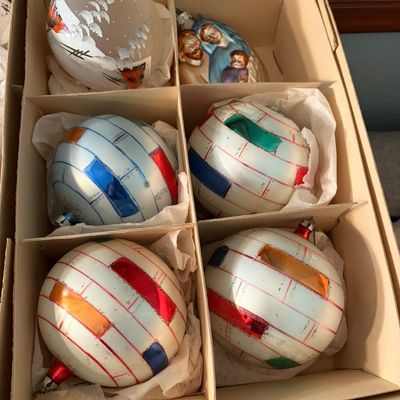 Sale Photo Thumbnail #90: Vintage glass Christmas ornaments in a cardboard storage box, featuring hand-painted winter scenes, a nativity figure, and colorful striped designs.
