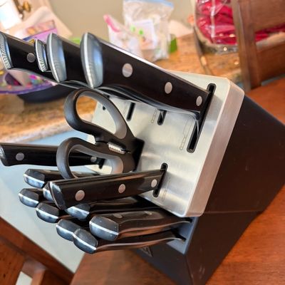 Sale Photo Thumbnail #56: Modern knife block set featuring black-handled knives and kitchen shears housed in a dark wood and stainless steel block.