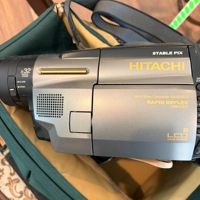 Sale Photo Thumbnail #52: Vintage Hitachi VM-E635LA 8mm video camcorder with 32x digital zoom and LCD color monitor, resting in a green carrying bag.