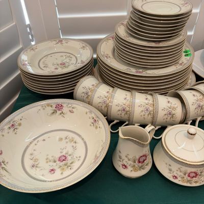 Sale Photo Thumbnail #43: Noritake fine china dinnerware set in the 'Shenandoah' pattern, featuring delicate pink and yellow floral motifs with gold trim, including plates, bowls, cups, a creamer, and a sugar bowl.