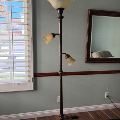 Sale Photo Thumbnail #40: Traditional bronze-finished torchiere floor lamp featuring a main uplight and two adjustable reading lights with frosted amber glass shades.
