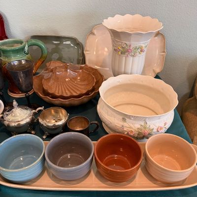Sale Photo Thumbnail #62: Assorted vintage tableware and decorative ceramics, including a set of four colorful nesting-style bowls on a tray, a white floral-embossed bowl and vase, brown shell-shaped dishes, and silver-plated serving pieces.