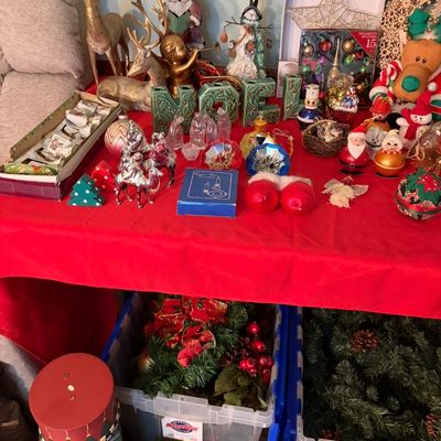 Sale Photo Thumbnail #95: Assortment of vintage and modern Christmas decorations, including reindeer figurines, a ceramic "NOEL" set, various ornaments, and storage bins filled with artificial greenery.