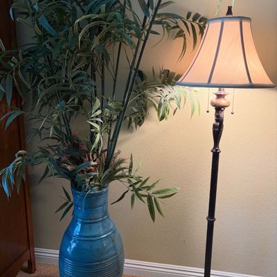 Sale Photo Thumbnail #71: Large blue ceramic floor vase filled with faux bamboo foliage, paired with a traditional dark metal floor lamp featuring a bell shade.