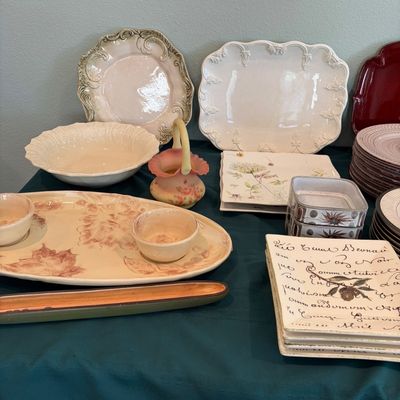 Sale Photo Thumbnail #58: Assortment of ceramic and porcelain tableware, featuring a leaf-patterned chip-and-dip platter, embossed white serving dishes, and script-printed square plates.