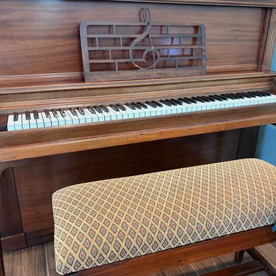 Sale Photo Thumbnail #61: Vintage upright piano in a dark wood finish, featuring a decorative treble clef music stand and an upholstered bench with a diamond pattern.