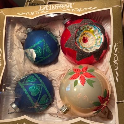 Sale Photo Thumbnail #91: Vintage Lanissa boxed set of four glass Christmas ornaments, featuring two blue glitter-accented balls, one white ball with painted poinsettias, and one red indented reflector ornament.