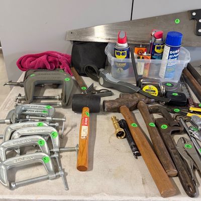 Sale Photo Thumbnail #80: Assortment of hand tools including C-clamps, hammers, pipe wrenches, pliers, a hand saw, and aerosol lubricants.