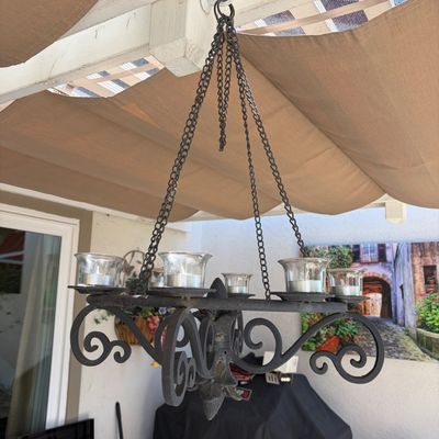 Sale Photo Thumbnail #17: Wrought iron hanging candle chandelier featuring scrollwork details and glass votive cups, suspended by a metal chain.