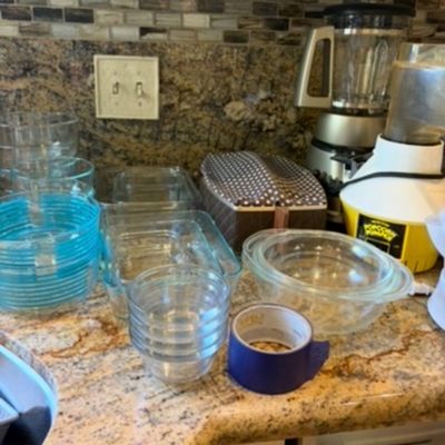 Sale Photo Thumbnail #24: Assorted kitchenware including Pyrex glass baking dishes, mixing bowls, a vintage popcorn popper, and a blender displayed on a granite countertop.