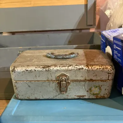 Vintage Union steel tackle box with a distressed, weathered finish, featuring a top handle and front latch.
