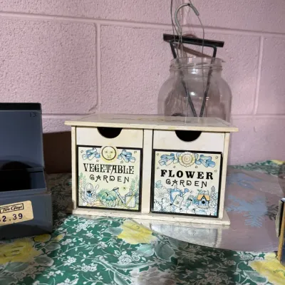 Vintage wooden two-drawer seed organizer box featuring illustrated labels for "Vegetable Garden" and "Flower Garden."