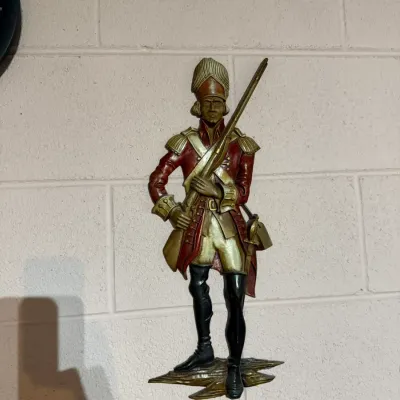 Vintage Sexton cast metal wall plaque depicting a Revolutionary War soldier in a red coat, holding a rifle.