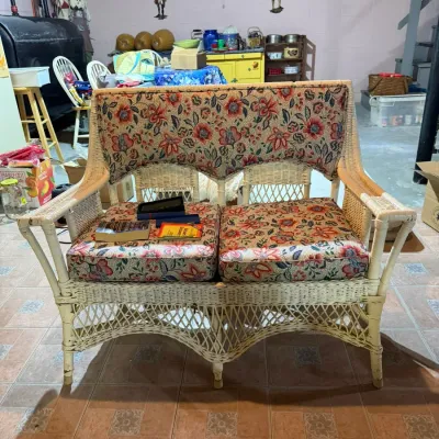 Vintage white wicker settee featuring a woven lattice design and floral patterned cushions.
