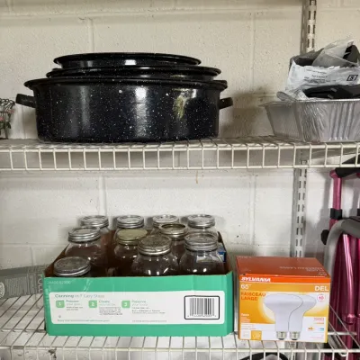 Vintage black speckled enamelware roasting pan with lid, shown alongside a box of canning jars and a package of Sylvania floodlights on...