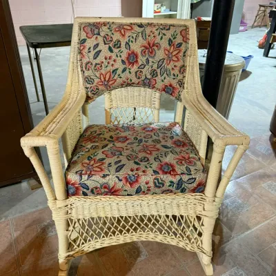 Vintage white wicker rocking chair featuring floral upholstered seat and back cushions in shades of red, blue, and green.