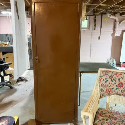 Vintage brown metal utility storage cabinet, showing some surface wear, suitable for garage or basement organization.