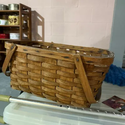 Vintage woven splint wood gathering basket with dual swing handles, showing some wear and age.