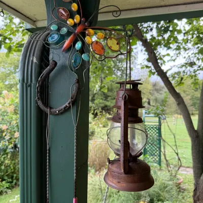 Vintage-style decorative metal butterfly with colorful glass inserts, paired with a rustic, weathered metal lantern hanging from a porch...