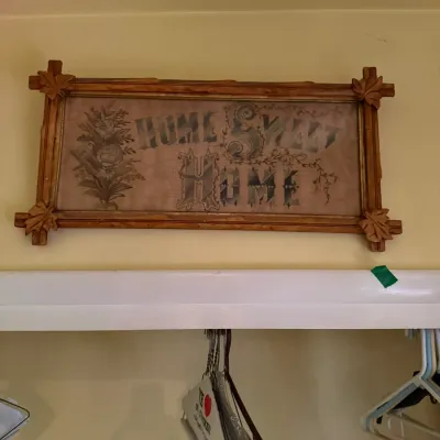 Antique framed "Home Sweet Home" needlepoint sampler, featuring an ornate carved wood frame with leaf details at the corners.