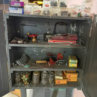 Vintage painted wooden tool cabinet filled with hand tools, hardware organizers, glass jars of fasteners, and vintage Phillies Blunt...