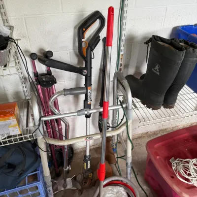 Assorted household and utility items, including a Carex folding walker, a Worx electric string trimmer, a mop with a red bucket, and a...