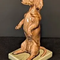 Vintage ceramic Villeroy and Boch dachshund figurine depicting a dog standing on its hind legs, mounted on a square green base.