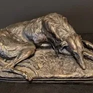 Antique bronze sculpture of a reclining Borzoi or Russian Wolfhound, featuring detailed textured fur and a dark patina finish. Vintage...