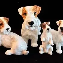 Collection of four vintage Royal Doulton porcelain terrier figurines, featuring realistic hand-painted details in white and brown.