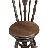 Antique wooden piano stool with a spindle back, swivel seat, and glass ball-and-claw feet.