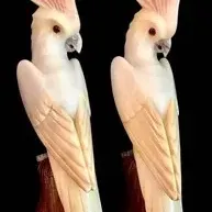 Pair of vintage hand-carved alabaster cockatoo figurines, featuring pink crests and perched on wooden bases.