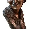 Antique bronze bust of a smiling woman, featuring detailed hair and a ruffled collar, mounted on a pedestal base.