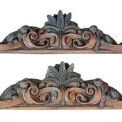 Pair of ornate carved wood pediments or architectural fragments featuring scrollwork and leaf motifs.