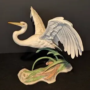 Boehm porcelain figurine of a white egret in flight over marsh grass, featuring detailed feathering and a matte finish.