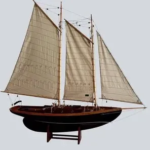 Detailed wooden model of a gaff-rigged schooner sailboat, complete with fabric sails, rigging, and a wooden display stand.