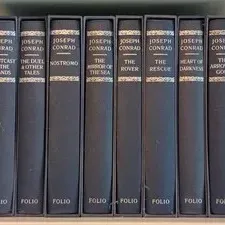 Eight-volume set of Joseph Conrad novels published by the Folio Society, featuring dark grey slipcases and spines with silver lettering.