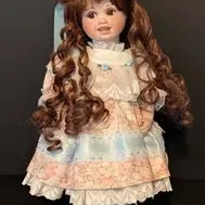 Vintage Porcelain Doll - Jerri McCloud Signed 18in.  Collectible porcelain doll featuring long curly brown hair with a blue bow, dressed...