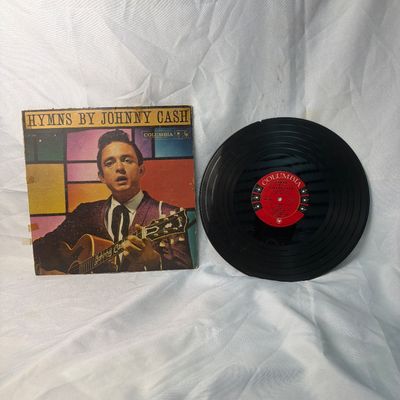 Sale Photo Thumbnail #41: Vintage vinyl record album 'Hymns by Johnny Cash' released on Columbia Records (CL 1284). Includes the original cardboard sleeve. The sleeve shows significant wear, including edge scuffing, discoloration, and tape residue. The vinyl record has a noticeabl