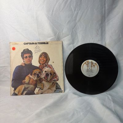 Sale Photo Thumbnail #35: Vintage 12-inch vinyl record album of Captain & Tennille's 'Love Will Keep Us Together' (1975). Includes the original cardboard sleeve featuring the duo with their bulldogs. The sleeve shows some age-related wear, edge scuffs, and a small price sticker on