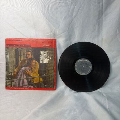 Sale Photo Thumbnail #28: Vintage vinyl record of the original soundtrack recording for "West Side Story" on Columbia Records (Stereo). Features the iconic red cover design. The cardboard sleeve shows some edge wear, corner scuffs, and a small price sticker on the front. The vinyl