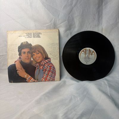 Sale Photo Thumbnail #36: Vintage 12-inch vinyl record album of Captain & Tennille's 'Love Will Keep Us Together' (1975). Includes the original cardboard sleeve featuring the duo with their bulldogs. The sleeve shows some age-related wear, edge scuffs, and a small price sticker on