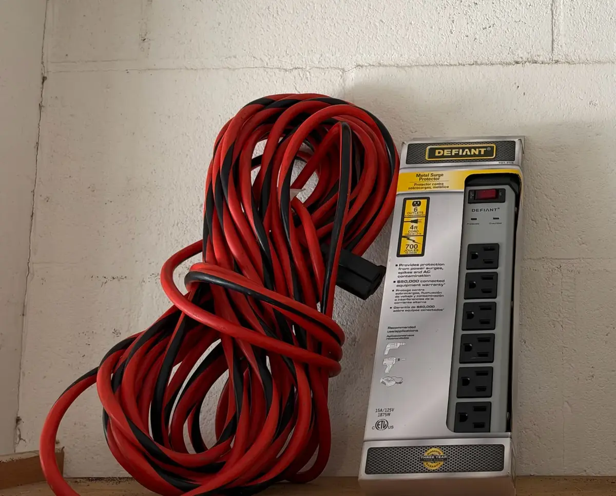 Defiant 6-Outlet Metal Surge Protector Package next to a Bundled Extension Cord