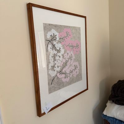 Framed floral art print featuring white and pink blossoms on a textured gray background, presented in a simple wood frame with a wide...