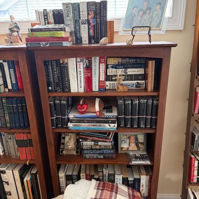 Wooden five-shelf bookcase filled with books, framed family photos, and small decorative items.