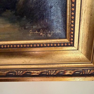 Detail of an oil painting signature dated 1913, housed in an ornate, beaded giltwood frame.