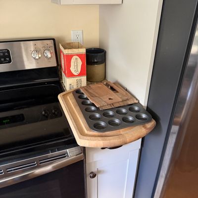Assorted kitchenware including a vintage Sunbeam hand mixer in its original box, a metal muffin tin, and several wooden cutting boards.